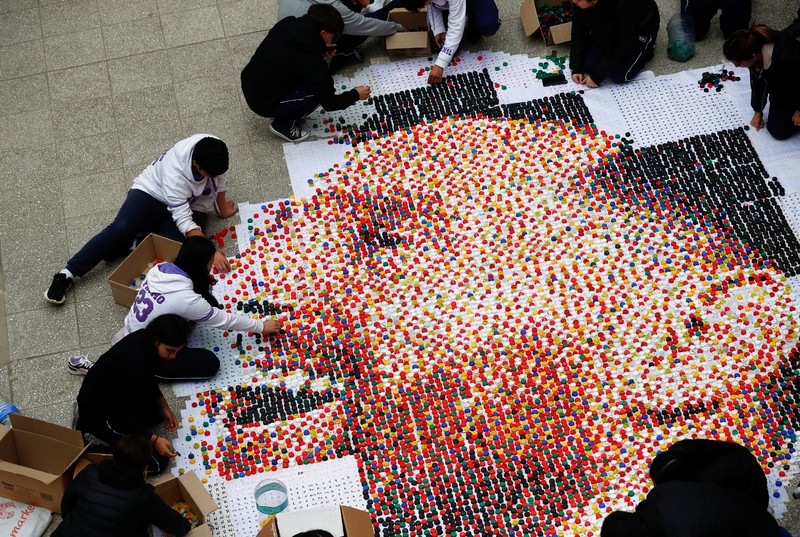 SOCCER-ARGENTINA/MESSI-TRIBUTE High school students stand next to the mural they made with plastic bottle caps depicting Argentina's soccer superstar Lionel Messi, nine months after Argentina won the soccer World Cup Qatar 2022, in Grand Bourg, on the outskirts of Buenos Aires, Argentina September 19, 2023. REUTERS/Agustin Marcarian