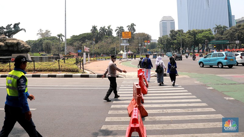 Warga berjalan di persimpangan lampu merah patung kuda, Jakarta, Senin, (25/9). (CNBC Indonesia/Muhammad Sabki)