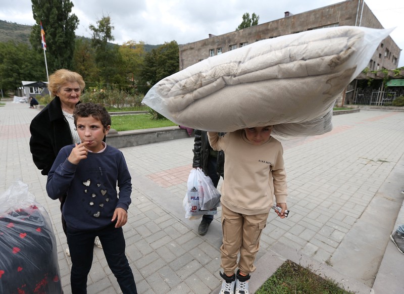 Warga berkumpul di samping bus di pusat Stepanakert sebelum meninggalkan Nagorno-Karabakh, wilayah yang dihuni etnis Armenia, 25 September 2023. (REUTERS/David Ghahramanyan)