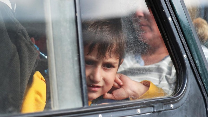 Warga berkumpul di samping bus di pusat Stepanakert sebelum meninggalkan Nagorno-Karabakh, wilayah yang dihuni etnis Armenia, 25 September 2023. (REUTERS/David Ghahramanyan)