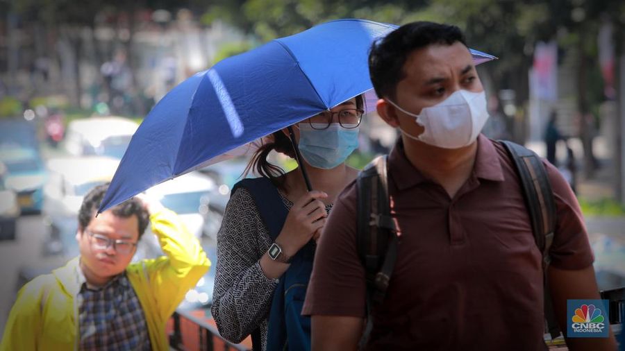 Pejalan kaki menggunakan payung untuk menghindari terik matahari di kawasan Jembatan Pinisi di halte busway Karet, Jakarta, Rabu (27/9/2023). (CNBC Indonesia/Muhammad Sabki)
