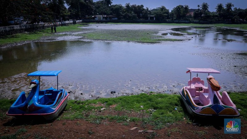 Seorang warga berjalan di tanah yang retak akibat kekeringan di Danau Cinere, Depok, Jawa Barat, Rabu (27/9/2023). (CNBC Indonesia/Faisal Rahman)