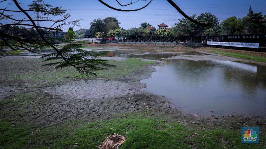 Seorang warga berjalan di tanah yang retak akibat kekeringan di Danau Cinere, Depok, Jawa Barat, Rabu (27/9/2023). (CNBC Indonesia/Faisal Rahman)