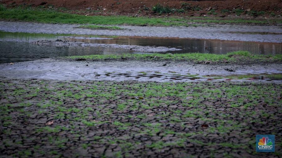 Seorang warga berjalan di tanah yang retak akibat kekeringan di Danau Cinere, Depok, Jawa Barat, Rabu (27/9/2023). (CNBC Indonesia/Faisal Rahman)