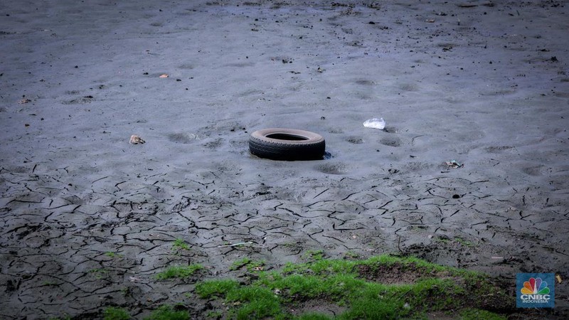 Seorang warga berjalan di tanah yang retak akibat kekeringan di Danau Cinere, Depok, Jawa Barat, Rabu (27/9/2023). (CNBC Indonesia/Faisal Rahman)