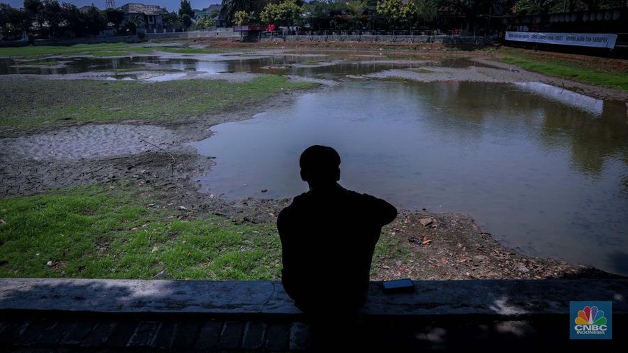 Seorang warga berjalan di tanah yang retak akibat kekeringan di Danau Cinere, Depok, Jawa Barat, Rabu (27/9/2023). (CNBC Indonesia/Faisal Rahman)