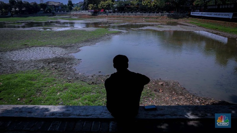 Seorang warga berjalan di tanah yang retak akibat kekeringan di Danau Cinere, Depok, Jawa Barat, Rabu (27/9/2023). (CNBC Indonesia/Faisal Rahman)