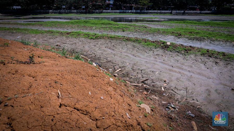 Seorang warga berjalan di tanah yang retak akibat kekeringan di Danau Cinere, Depok, Jawa Barat, Rabu (27/9/2023). (CNBC Indonesia/Faisal Rahman)