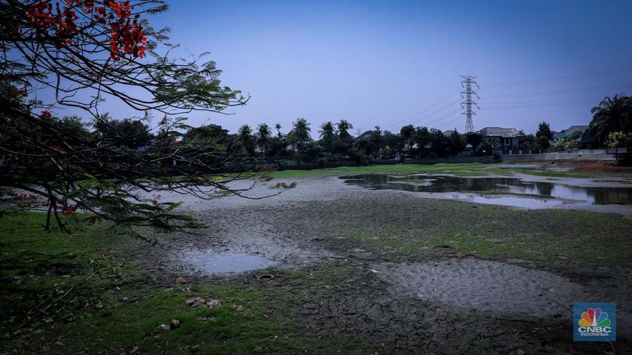 Seorang warga berjalan di tanah yang retak akibat kekeringan di Danau Cinere, Depok, Jawa Barat, Rabu (27/9/2023). (CNBC Indonesia/Faisal Rahman)