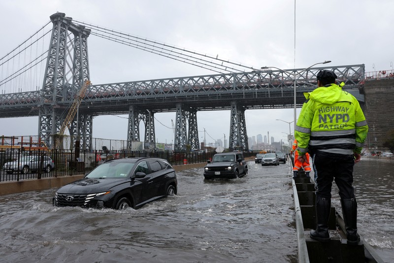 USA-WEATHER/ A police officer from the NYPD Highway Patrol looks to motorists drive through a flooded street after heavy rains as the remnants of Tropical Storm Ophelia bring flooding across the mid-Atlantic and Northeast, at the FDR Drive in Manhattan near the Williamsburg Bridge, in New York City, U.S., September 29, 2023. REUTERS/Andrew Kelly TPX IMAGES OF THE DAY
