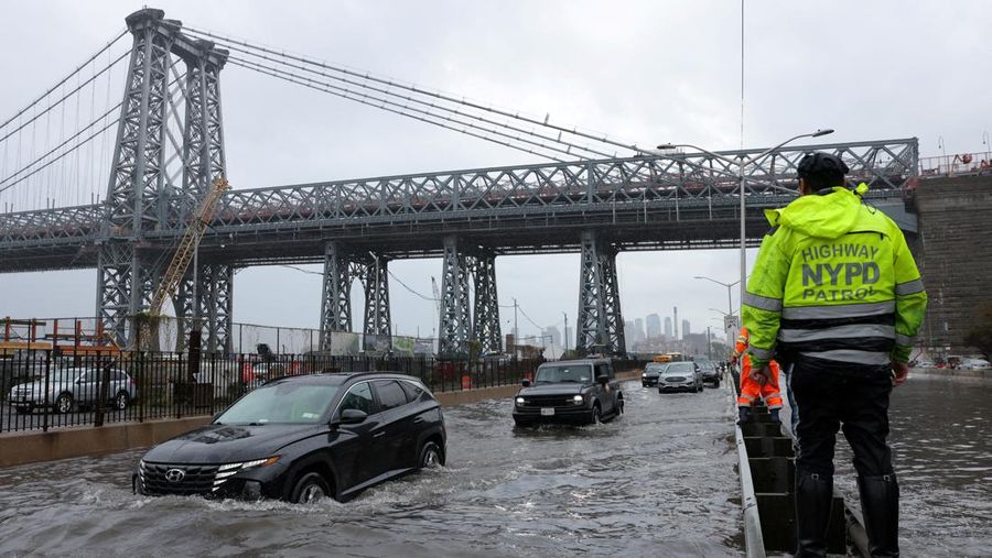 A police officer from the NYPD Highway Patrol looks to motorists drive through a flooded street after heavy rains as the remnants of Tropical Storm Ophelia bring flooding across the mid-Atlantic and Northeast, at the FDR Drive in Manhattan near the Williamsburg Bridge, in New York City, U.S., September 29, 2023.  REUTERS/Andrew Kelly     TPX IMAGES OF THE DAY