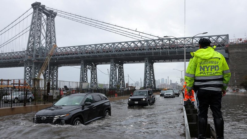 A police officer from the NYPD Highway Patrol looks to motorists drive through a flooded street after heavy rains as the remnants of Tropical Storm Ophelia bring flooding across the mid-Atlantic and Northeast, at the FDR Drive in Manhattan near the Williamsburg Bridge, in New York City, U.S., September 29, 2023.  REUTERS/Andrew Kelly     TPX IMAGES OF THE DAY