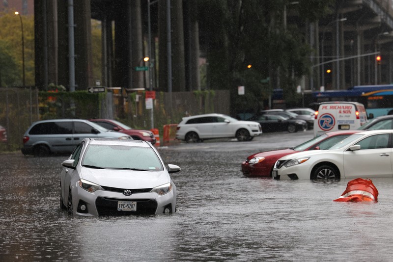 A police officer from the NYPD Highway Patrol looks to motorists drive through a flooded street after heavy rains as the remnants of Tropical Storm Ophelia bring flooding across the mid-Atlantic and Northeast, at the FDR Drive in Manhattan near the Williamsburg Bridge, in New York City, U.S., September 29, 2023.  REUTERS/Andrew Kelly     TPX IMAGES OF THE DAY