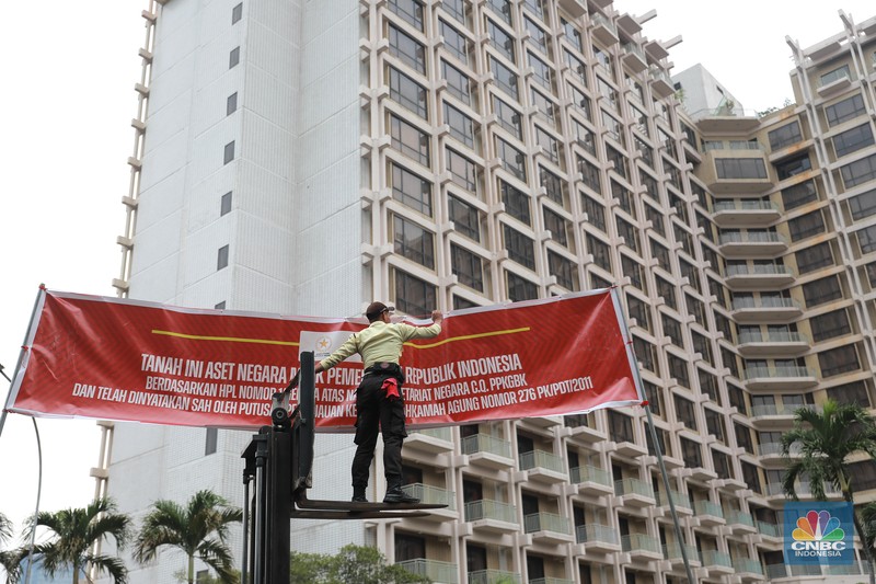 Petugas keamanan GBK memasang spanduk penyegelan Hotel Sultan di Kawasan Hitel Sultan, GBK, Jakarta, Rabu (4/10). (CNBC Indonesia/Muhammad Sabki)