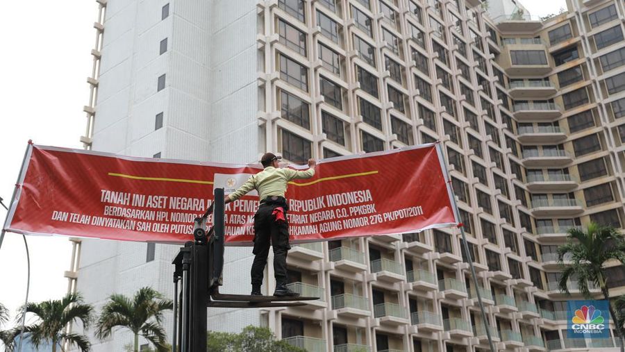 Petugas keamanan GBK memasang spanduk penyegelan Hotel Sultan di Kawasan Hitel Sultan, GBK, Jakarta, Rabu (4/10). (CNBC Indonesia/Muhammad Sabki)