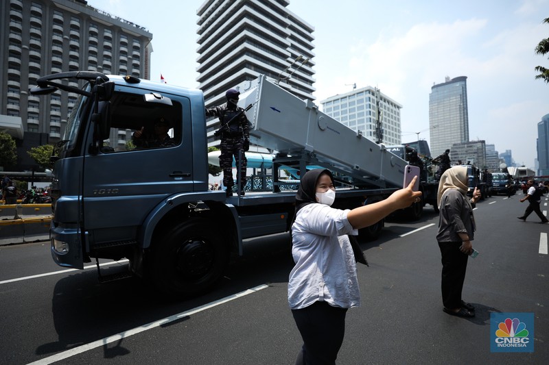 Warga menyaksikan parade militer HUT TNI ke 78 di Jakarta, Kamis (5/10/2023). (CNBC Indonesia/Tri Susilo)