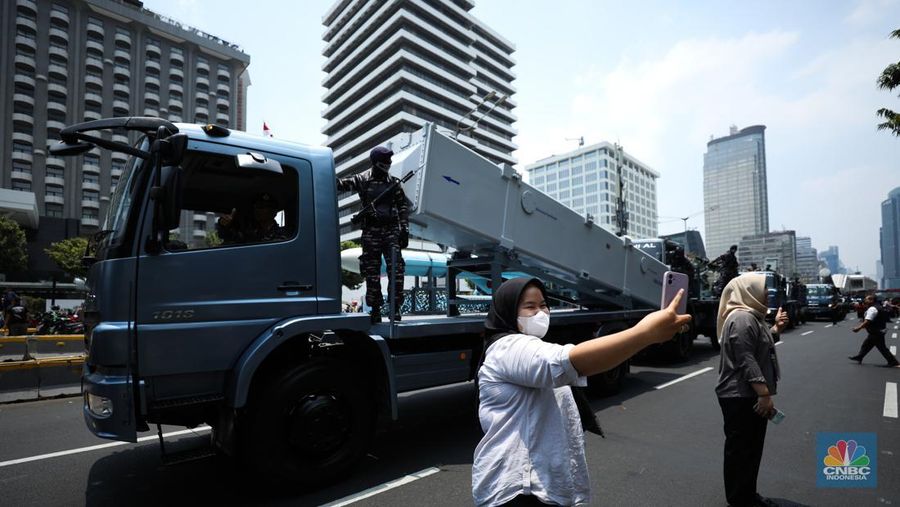 Warga menyaksikan parade militer HUT TNI ke 78 di Jakarta, Kamis (5/10/2023). (CNBC Indonesia/Tri Susilo)