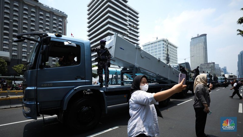 Warga menyaksikan parade militer HUT TNI ke 78 di Jakarta, Kamis (5/10/2023). (CNBC Indonesia/Tri Susilo)