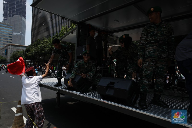 Warga menyaksikan parade militer HUT TNI ke 78 di Jakarta, Kamis (5/10/2023). (CNBC Indonesia/Tri Susilo)