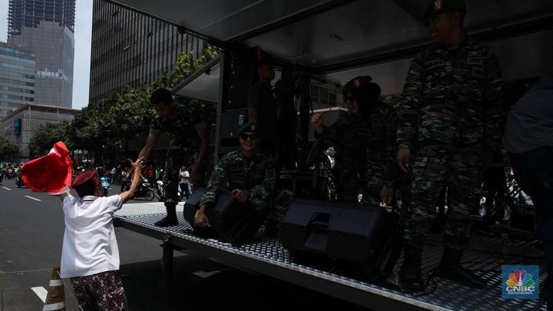 Warga menyaksikan parade militer HUT TNI ke 78 di Jakarta, Kamis (5/10/2023). (CNBC Indonesia/Tri Susilo)
