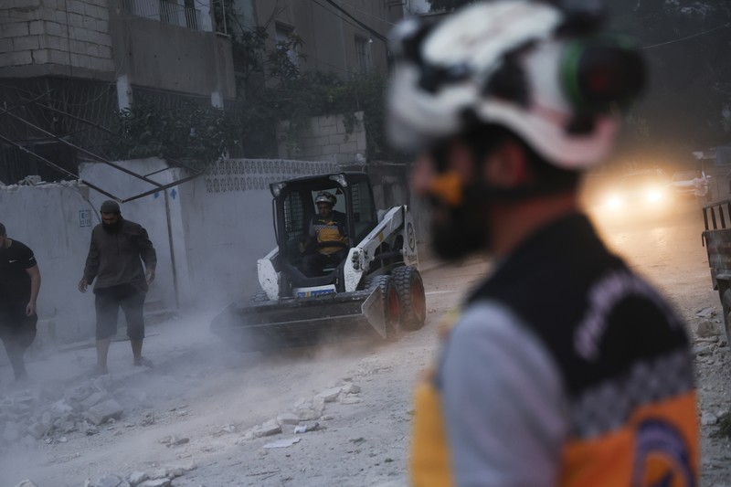 Dalam foto yang disediakan oleh Helm Putih Pertahanan Sipil Suriah, seorang pekerja pertahanan sipil Helm Putih Suriah berlari di lokasi serangan peluru di pinggiran kota utara Jisr al-Shoughour, sebelah barat kota Idlib, Suriah, Kamis , 5 Oktober 2023. Dalam foto yang disediakan oleh Helm Putih Pertahanan Sipil Suriah, seorang pekerja pertahanan sipil Helm Putih Suriah berlari di lokasi serangan peluru di pinggiran kota utara Jisr al-Shoughour, sebelah barat kota Idlib, Suriah, Kamis , 5 Oktober 2023. Serangan pesawat tak berawak menghantam upacara wisuda perwira militer yang penuh sesak di kota Homs, Suriah pada hari Kamis, menewaskan dan melukai puluhan laporan. Setelah serangan pesawat tak berawak, pemerintah menembaki desa-desa di provinsi Idlib, di bagian barat laut negara yang dikuasai pemberontak. (Syrian Civil Defense White Helmets via AP)