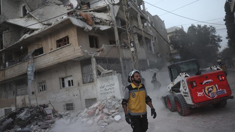Dalam foto yang disediakan oleh Helm Putih Pertahanan Sipil Suriah, seorang pekerja pertahanan sipil Helm Putih Suriah berlari di lokasi serangan peluru di pinggiran kota utara Jisr al-Shoughour, sebelah barat kota Idlib, Suriah, Kamis , 5 Oktober 2023. Serangan pesawat tak berawak menghantam upacara wisuda perwira militer yang penuh sesak di kota Homs, Suriah pada hari Kamis, menewaskan dan melukai puluhan laporan. Setelah serangan pesawat tak berawak, pemerintah menembaki desa-desa di provinsi Idlib, di bagian barat laut negara yang dikuasai pemberontak. (Syrian Civil Defense White Helmets via AP)