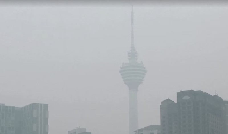 Pria berjalan melewati Pusat Kota Kuala Lumpur yang diselimuti kabut di Kuala Lumpur, Malaysia 3 Oktober 2023. (REUTERS/Hasnoor Hussain)