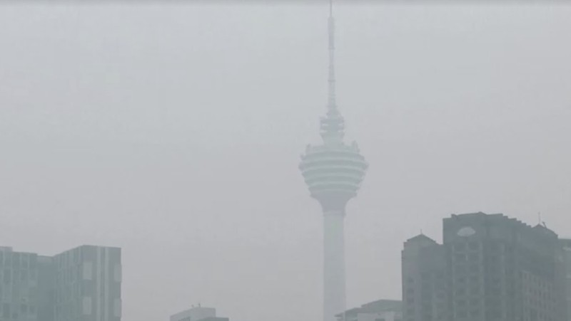 Pria berjalan melewati Pusat Kota Kuala Lumpur yang diselimuti kabut di Kuala Lumpur, Malaysia 3 Oktober 2023. (REUTERS/Hasnoor Hussain)