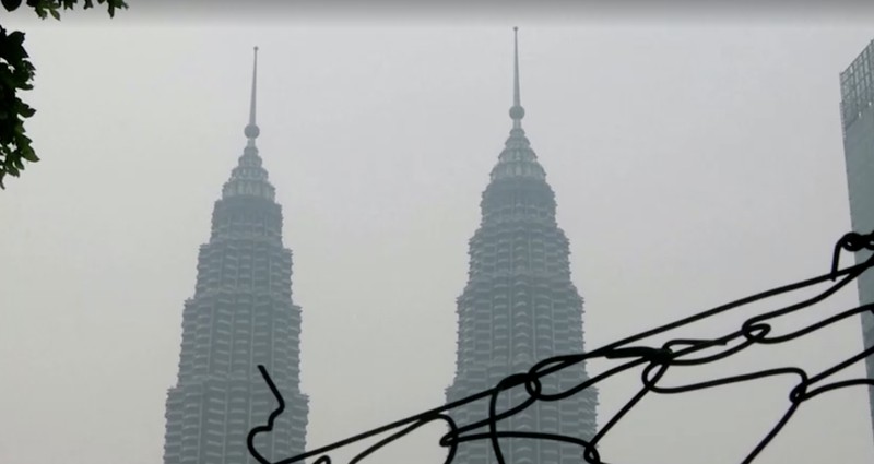 Pria berjalan melewati Pusat Kota Kuala Lumpur yang diselimuti kabut di Kuala Lumpur, Malaysia 3 Oktober 2023. (REUTERS/Hasnoor Hussain)