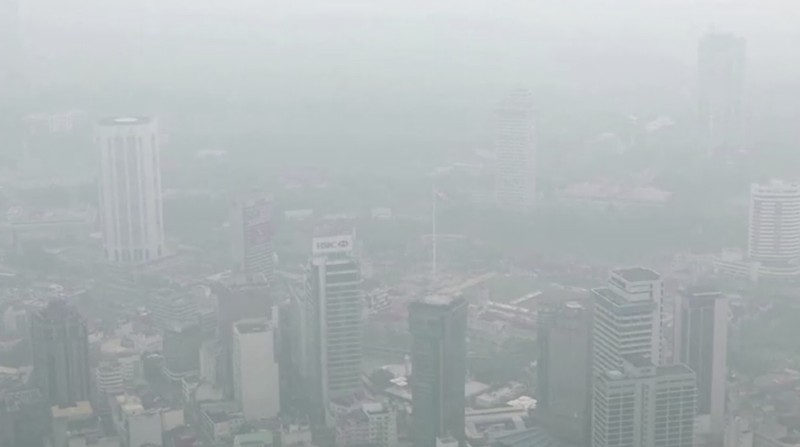 Pria berjalan melewati Pusat Kota Kuala Lumpur yang diselimuti kabut di Kuala Lumpur, Malaysia 3 Oktober 2023. (REUTERS/Hasnoor Hussain)