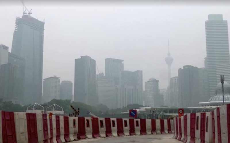 Pria berjalan melewati Pusat Kota Kuala Lumpur yang diselimuti kabut di Kuala Lumpur, Malaysia 3 Oktober 2023. (REUTERS/Hasnoor Hussain)