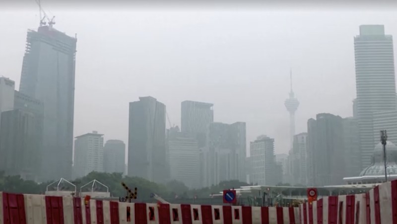 Pria berjalan melewati Pusat Kota Kuala Lumpur yang diselimuti kabut di Kuala Lumpur, Malaysia 3 Oktober 2023. (REUTERS/Hasnoor Hussain)
