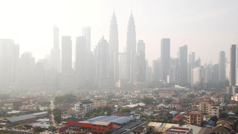 Pria berjalan melewati Pusat Kota Kuala Lumpur yang diselimuti kabut di Kuala Lumpur, Malaysia 3 Oktober 2023. (REUTERS/Hasnoor Hussain)