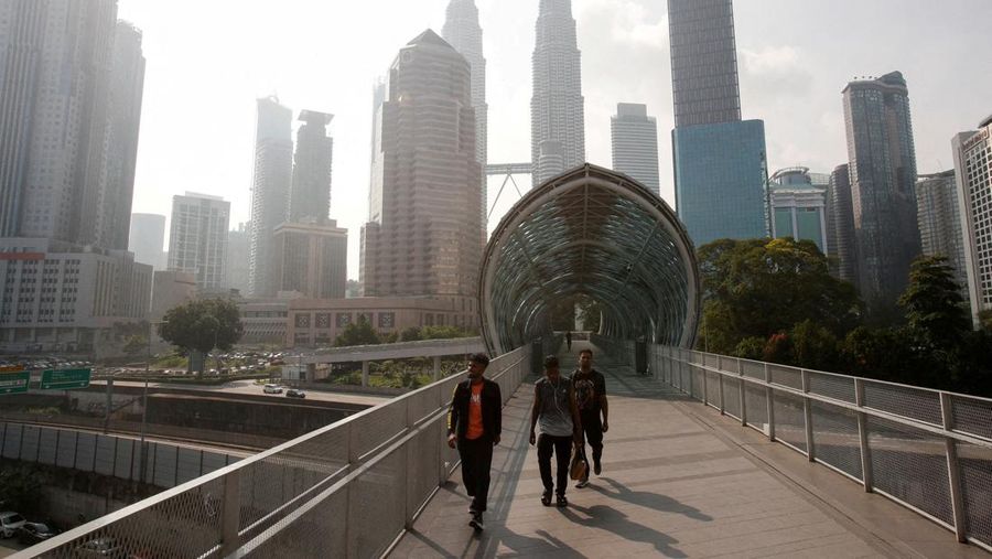 Pria berjalan melewati Pusat Kota Kuala Lumpur yang diselimuti kabut di Kuala Lumpur, Malaysia 3 Oktober 2023. (REUTERS/Hasnoor Hussain)