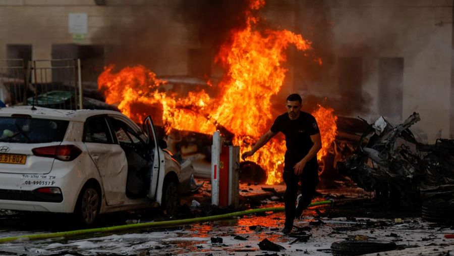 Seorang pria berlari di jalan saat api berkobar setelah roket diluncurkan dari Jalur Gaza, di Ashkelon, Israel 7 Oktober 2023. (REUTERS/Amir Cohen)