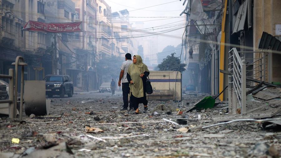 A Palestinian woman looks on as she walks on a debris-strewn street near the Watan Tower, which was destroyed in Israeli strikes, in Gaza City October 8, 2023. REUTERS/Mohammed Salem