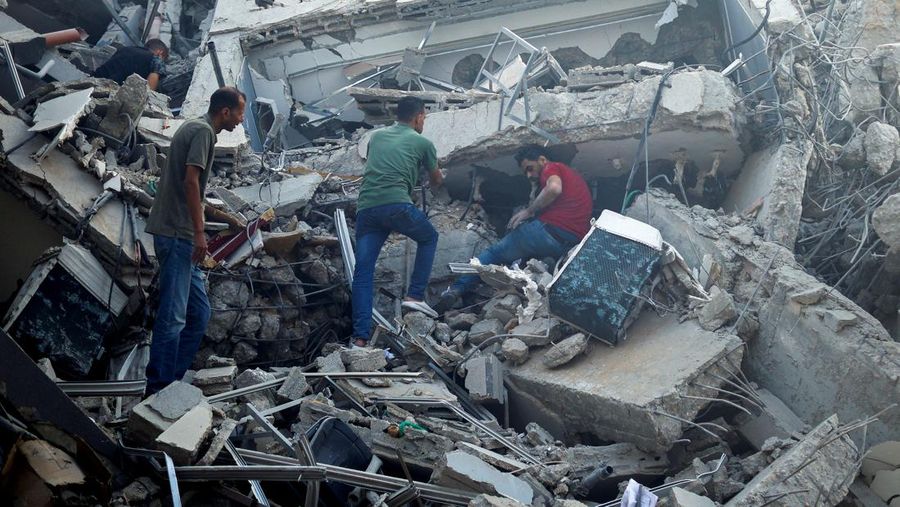 Palestinian search for belongings in the rubble of the Watan Tower, which was destroyed in Israeli strikes, in Gaza City October 8, 2023. REUTERS/Mohammed Salem