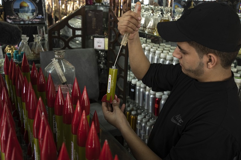 Belal Abu Saraya poses with a perfume container representing rockets used against Israel in a perfume store against Israel in past conflicts at his shop in Gaza City on Thursday, Oct. 5, 2023. AP Photo/Fatima Shbair)