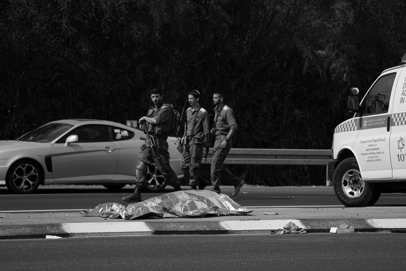 Israel Palestinians Israeli soldiers walk by a killed Palestinian militant near the Gaza strip outside Ashkelon, Israel, on Saturday, Oct. 7, 2023. Palestinian militants in the Gaza Strip infiltrated Saturday into southern Israel and fired thousands of rockets into the country while Israel began striking targets in Gaza in response. (AP Photo/Ohad Zwigenberg)