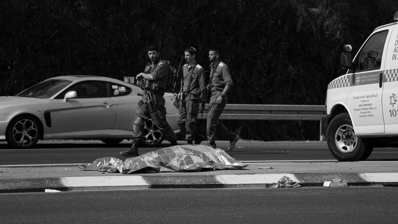 Israeli soldiers walk by a killed Palestinian militant near the Gaza strip outside Ashkelon, Israel, on Saturday, Oct. 7, 2023. Palestinian militants in the Gaza Strip infiltrated Saturday into southern Israel and fired thousands of rockets into the country while Israel began striking targets in Gaza in response. (AP Photo/Ohad Zwigenberg)