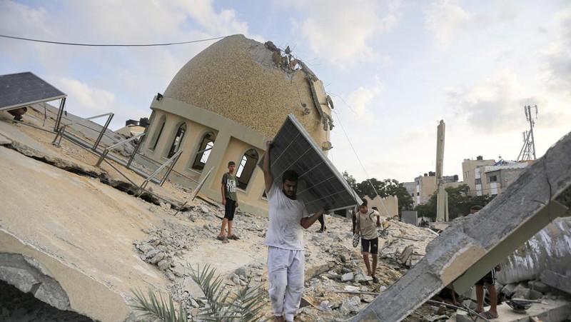 Rockets are fired from the Gaza Strip toward Israel over destroyed buildings following Israeli airstrikes on Gaza City, central Gaza Strip, Thursday, Oct. 19, 2023. (AP Photo/Mohammed Dahman)