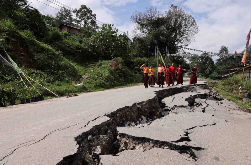 INDIA-FLOODS/ Monks walk along a road with cracks caused by flash floods in Naga-Namgor village, Sikkim, India, October 10, 2023. REUTERS/Francis Mascarenhas