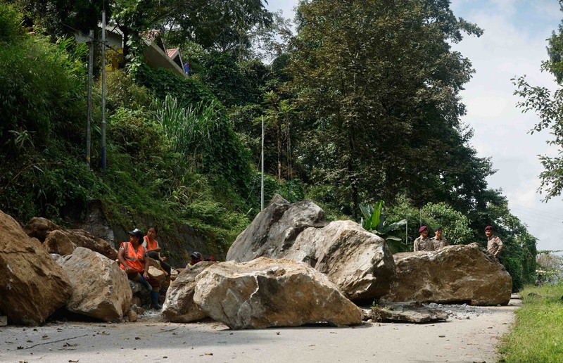 Monks walk along a road with cracks caused by flash floods in Naga-Namgor village, Sikkim, India, October 10, 2023. REUTERS/Francis Mascarenhas
