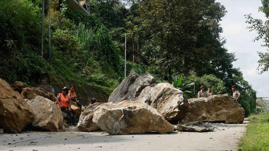 Monks walk along a road with cracks caused by flash floods in Naga-Namgor village, Sikkim, India, October 10, 2023. REUTERS/Francis Mascarenhas