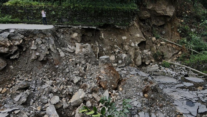Monks walk along a road with cracks caused by flash floods in Naga-Namgor village, Sikkim, India, October 10, 2023. REUTERS/Francis Mascarenhas