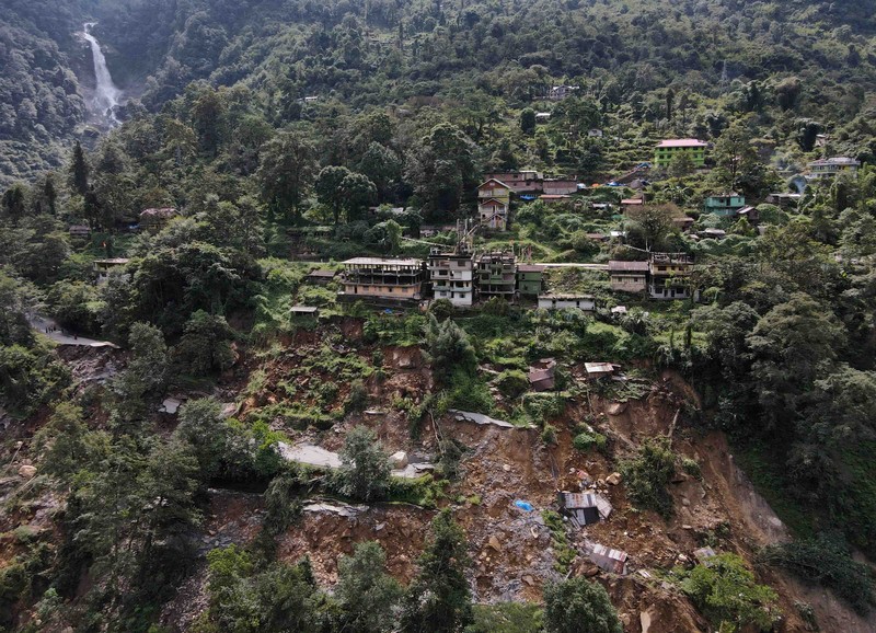 Monks walk along a road with cracks caused by flash floods in Naga-Namgor village, Sikkim, India, October 10, 2023. REUTERS/Francis Mascarenhas