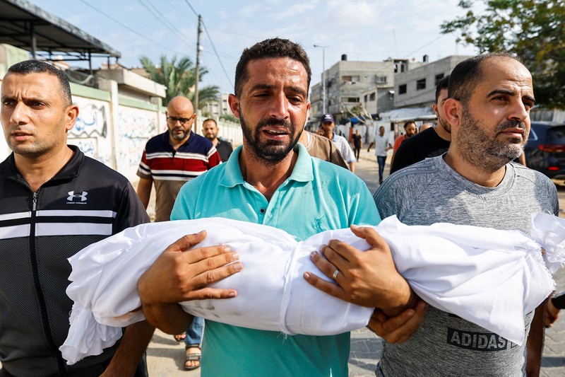 A medic runs as he carries an injured Palestinian child to ambulance in this screengrab taken from a video, in Gaza, October 9, 2023. REUTERS/Stringer NO RESALES. NO ARCHIVES     TPX IMAGES OF THE DAY
