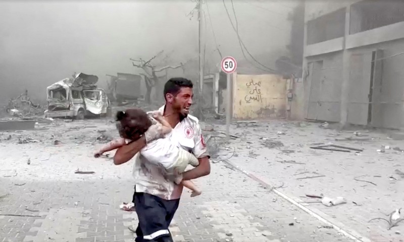 ISRAEL-PALESTINIANS/ A medic runs as he carries an injured Palestinian child to ambulance in this screengrab taken from a video, in Gaza, October 9, 2023. REUTERS/Stringer NO RESALES. NO ARCHIVES TPX IMAGES OF THE DAY