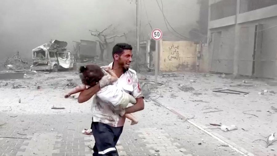 A medic runs as he carries an injured Palestinian child to ambulance in this screengrab taken from a video, in Gaza, October 9, 2023. REUTERS/Stringer NO RESALES. NO ARCHIVES     TPX IMAGES OF THE DAY