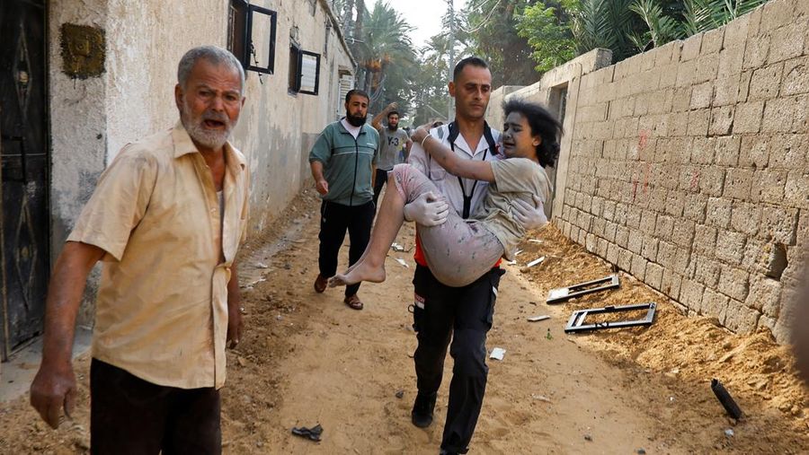A man carries a wounded Palestinian girl at the site of Israeli strikes on houses, in Khan Younis in the southern Gaza Strip  October 11, 2023. REUTERS/Ibraheem Abu Mustafa
